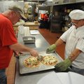 Joe Dukeshire, left, cuts pizza slices as Fred Krause holds the tray while preparing lunch Tuesday a...