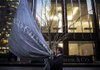 Workers raise a JPMorgan Chase & Co. flag at company headquarters before an annual Investors Day conference in New York, U.S., on Tuesday, Feb. 26, 2013. JPMorgan Chase & Co., the biggest U.S. bank, expects headcount to decline by about 4,000 in 2013 as Chief Executive officer Jamie Dimon targets mortgage operations for cuts. Photographer: Victor J. Blue/Bloomberg