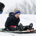 Layton Huffman, 4, sleds down a hillside at Country Club Golf Course as his father, Todd, looks on i...