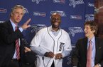 Detroit Tigers outfielder Torii Hunter, smiles after putting on his jersey as team general manager David Dombrowski, left, and owner Mike Ilitch look on before a news conference in Detroit, Friday, Nov. 16, 2012. Hunter, who last played for the Los Angeles Angels, signed a two-year, $26 million deal. (AP Photo/Carlos Osorio)