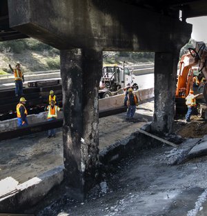 Arkansas Highway and Transportation Department crews begin work Friday on reinforcing concrete columns on the Young Road overpass at Interstate 40 in North Little Rock after Thursday’s fi ery crash. 