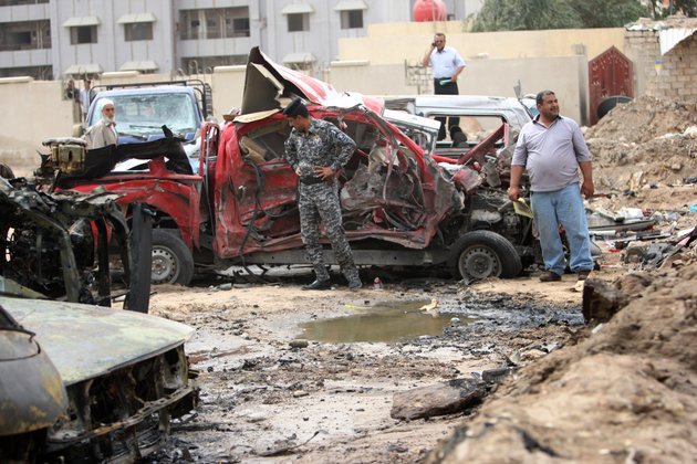 an-iraqi-policeman-and-civilians-inspect-the-site-of-a-car-bomb-attack-in-basra-iraq-sunday-march-17-2013-iraqi-authorities-say-two-car-bombs-have-killed-several-people-and-wounded-scores-of-others-in-the-countrys-south