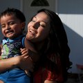 Leslie Silva, 18, laughs as she carries her son, Noah Mauricio, 18 months, outside her home in Sprin...