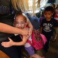 Alli Cox, 6, center, gives her kindergarten teacher Bonnie Bedford a goodbye hug Friday as classmate...