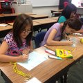 Elizabeth Sanchez, 10, left, and Joselin Villasenor, 12, write vowels Wednesday at J.O. Kelly Middle...