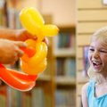 Magician Marty Boone finishes a balloon hat Thursday for Carrie Carter, 6, of Springdale during a pe...