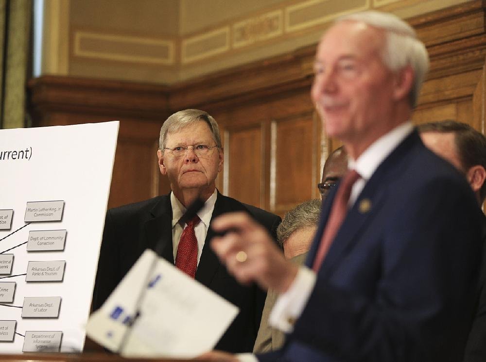 Mike Carroll (left), chairman of Gov. Asa Hutchinson’s Transformation Advisory Board, appears with Hutchinson at the state Capitol on Wednesday as Hutchinson announces his state government reorganization plan.